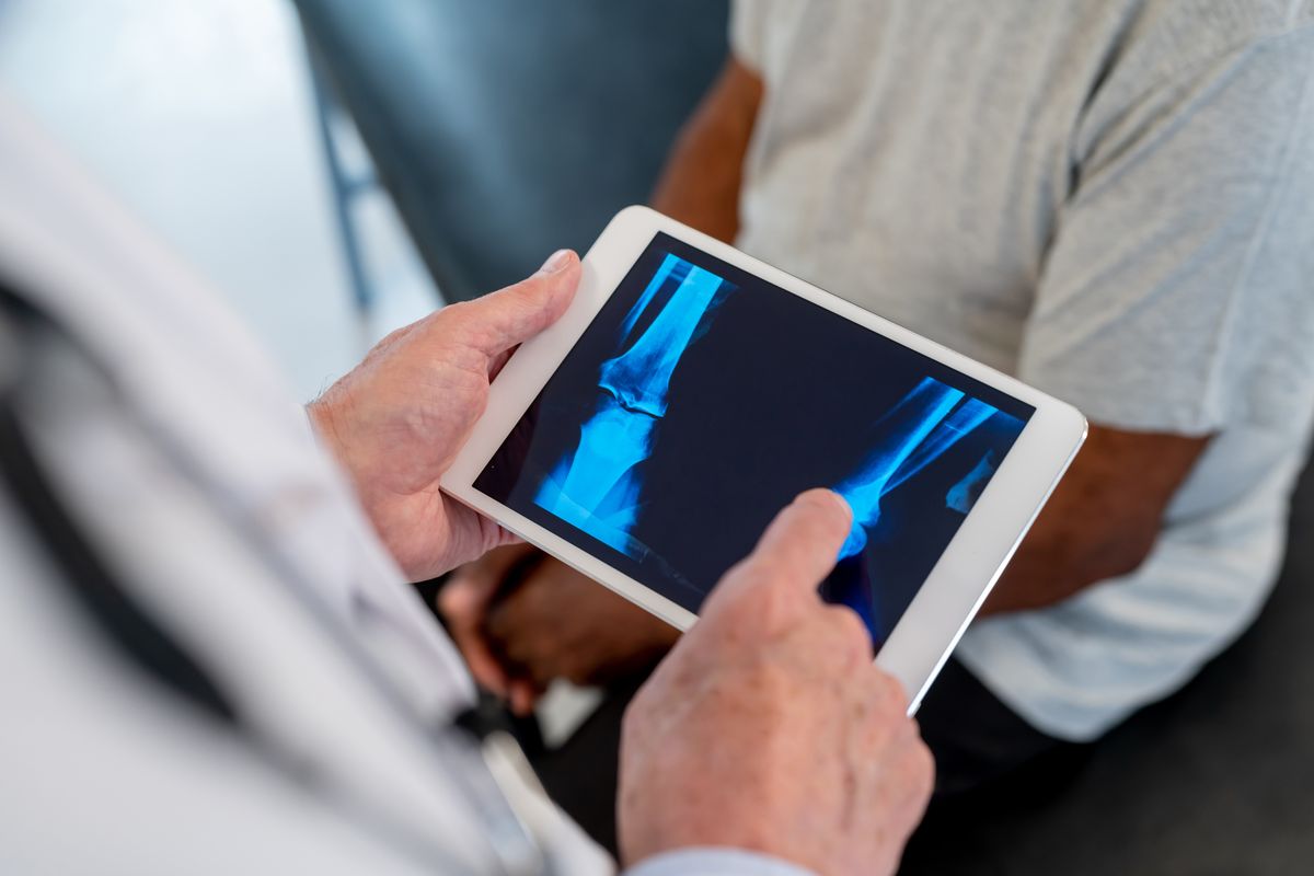 Orthopedic surgeon conducting a detailed consultation with a patient to assess hip or knee condition